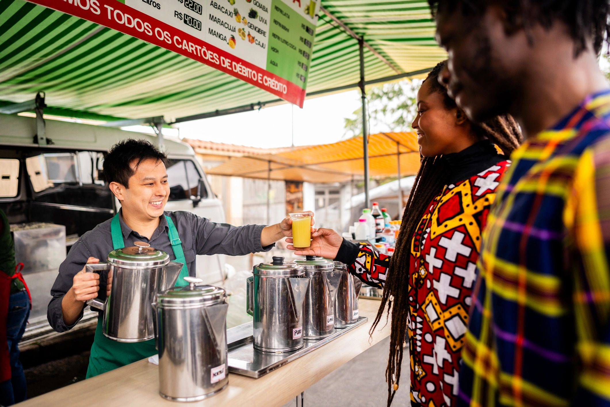 Sugarcane juice salesman serving customers at a street kiosk
