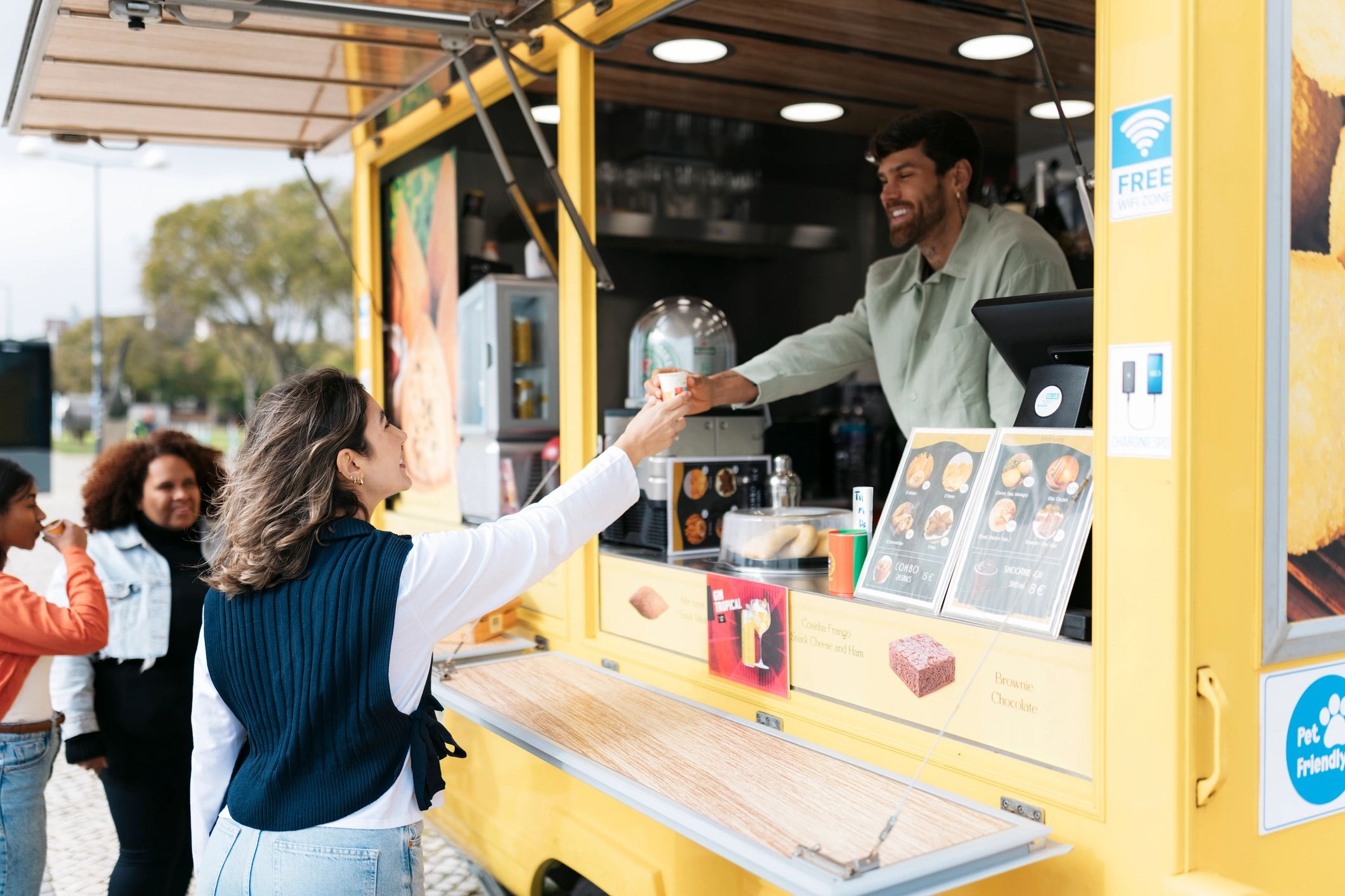 Woman receiving a cup of coffee from a food truck vendor
