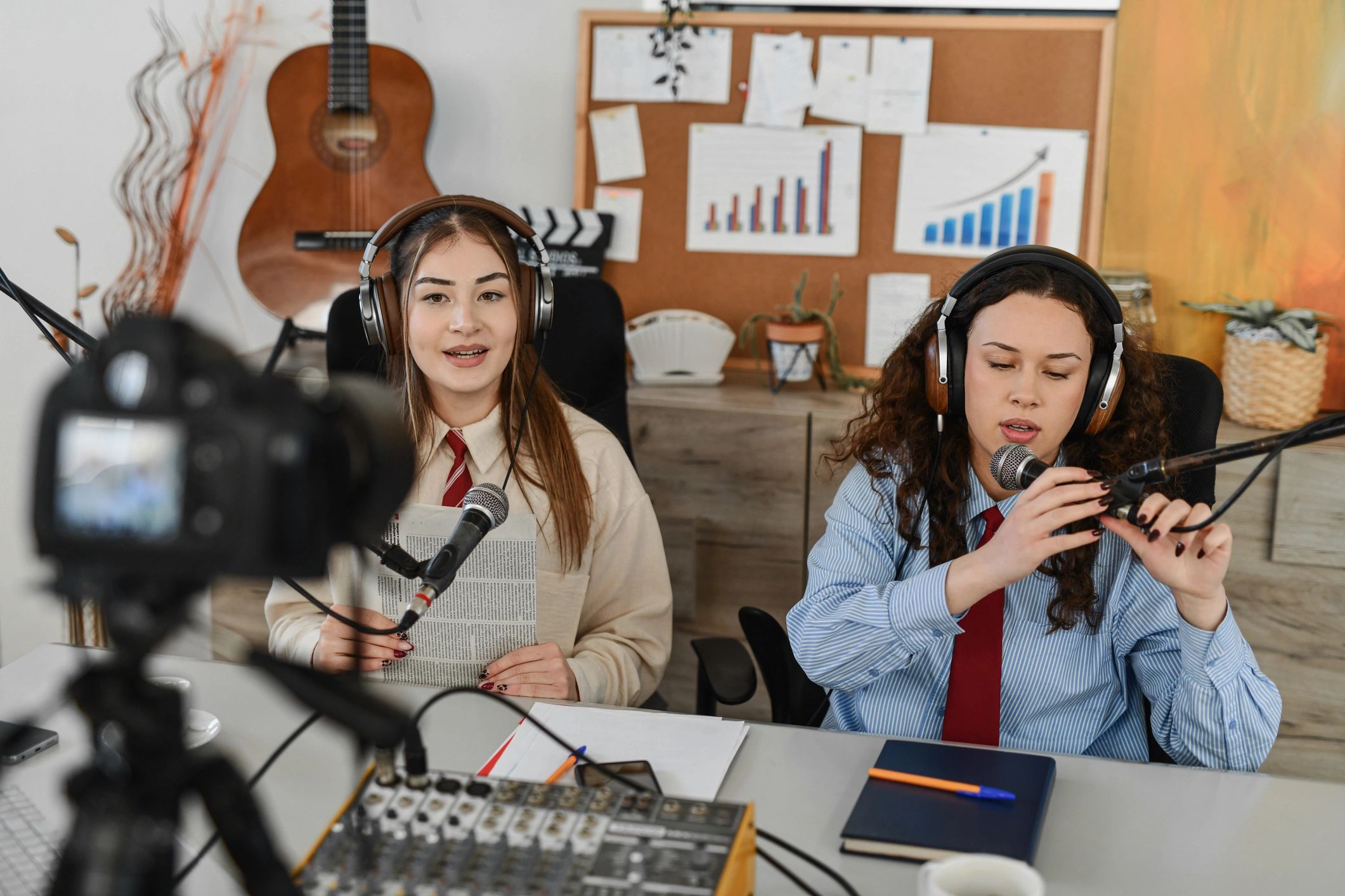 Two podcast hosts laughing together during a studio recording session
