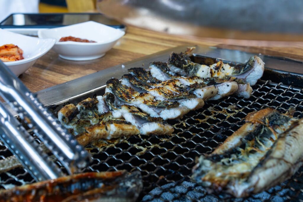 Sliced grilled eel fillets neatly arranged on a charcoal wire rack